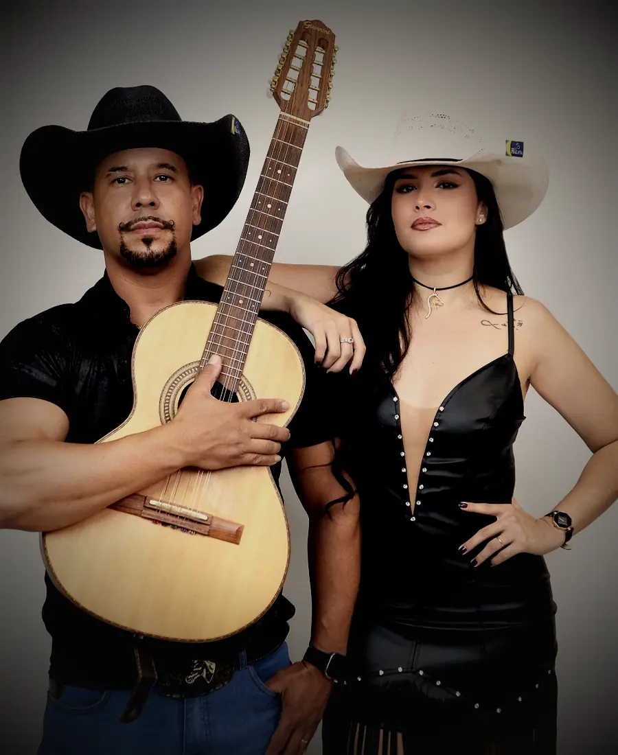 Henrique e Bianca no palco, de chapéu, com violão